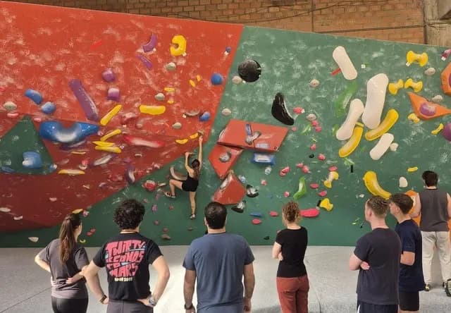 Bewoners van HOC Living kijken samen toe bij een klimuitje in een boulderhal