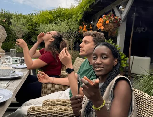 Colivingbewoners eten samen aan een lange tafel in de tuin van een HOC Living-huis
